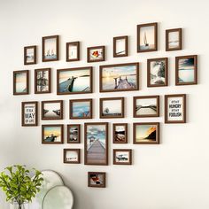 there are many frames on the wall with pictures hanging above it and a vase in front