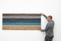 a man is holding up a large piece of wood that has been painted with multicolored stripes