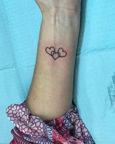 a woman's wrist with two hearts tattooed on the left side of her arm