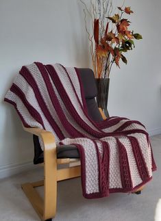 a chair with a crocheted blanket on it next to a potted plant