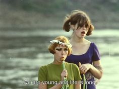 two young women standing next to each other holding umbrellas and flowers in their hair