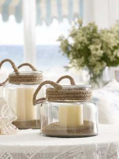 two jars filled with candles sitting on top of a table