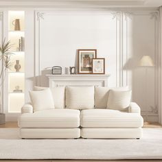 a living room with white couches and pillows on the floor in front of a fireplace