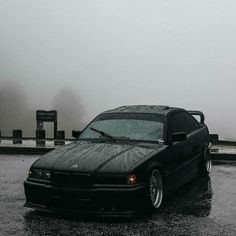 a black car is parked in the rain