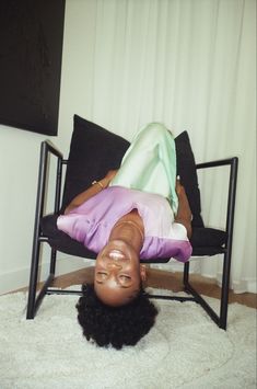 a woman laying on top of a black chair