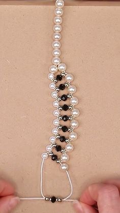 a person holding a string with pearls and black beads