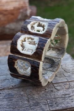 two wooden bracelets sitting on top of a piece of wood with carved animal designs