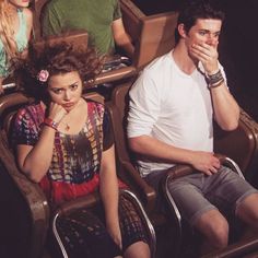 three people sitting in chairs with one woman covering her mouth and the other man standing behind them