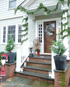 the front porch is decorated for christmas with greenery and potted plants on the steps