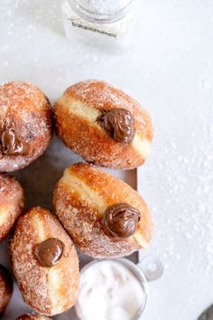 chocolate covered doughnuts are arranged on a plate next to a glass of milk