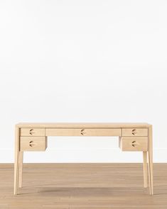 a wooden desk sitting on top of a hard wood floor next to a white wall