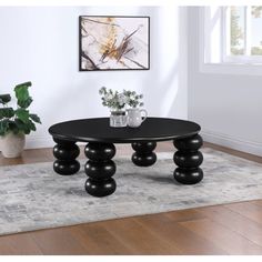 a black coffee table sitting on top of a wooden floor next to a potted plant