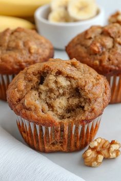 three banana muffins sitting on top of a white plate next to some nuts