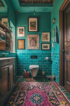 a bathroom with blue tiles and pictures on the wall above the toilet, along with a rug