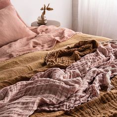 an unmade bed with pink and brown sheets