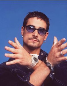 a man wearing sunglasses and holding his hands in front of him with both hands out