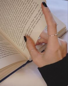 a woman is reading a book with her finger in the middle