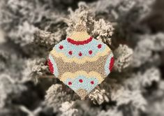 an ornament hanging from a tree branch with snow flakes on the branches