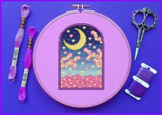 a cross stitch project with scissors, thread and spools on a purple background