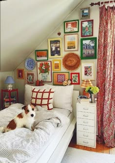 a dog laying on top of a bed in a room with many pictures and paintings