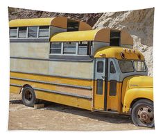 an old yellow school bus parked in front of a rock wall with two doors open