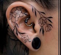 an ear tattoo with flowers and leaves on it