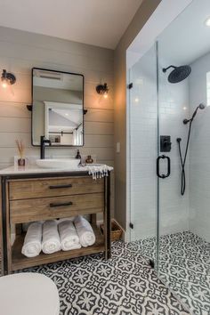 a bathroom with a sink, toilet and shower stall in the middle of it that has black and white tiles on the floor