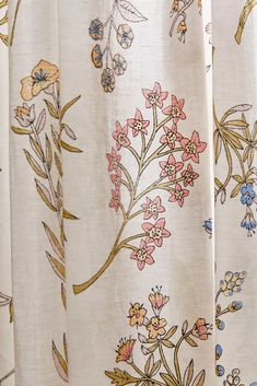 the curtain is decorated with colorful flowers and leaves on white fabric, as well as gold trimmings