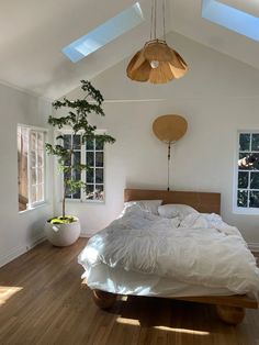 a bed sitting on top of a wooden floor in a bedroom next to two windows