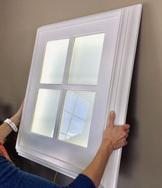 a woman is painting a window with white paint