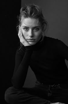 a black and white photo of a woman with her hand on her face sitting down