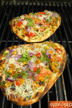 two pizzas sitting on top of a grill covered in cheese and veggies