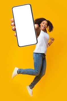 a woman jumping in the air while holding up a cell phone with a white screen