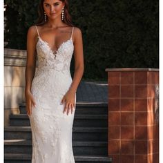 a woman in a white wedding dress standing on steps with her hand on her hip