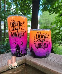 two purple and orange painted wine glasses sitting on top of a wooden table next to each other