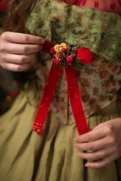 a woman wearing a red ribbon around her waist and holding something in her other hand