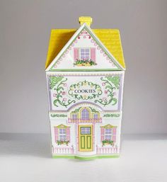 a small white and yellow doll house with pink trimmings on the front door