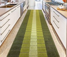 a kitchen with green and yellow rugs on the floor next to white cupboards