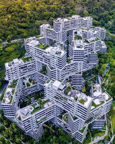 an aerial view of many buildings in the middle of trees and grass on top of them