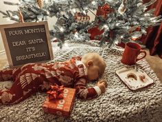 a baby laying on the floor next to a christmas tree