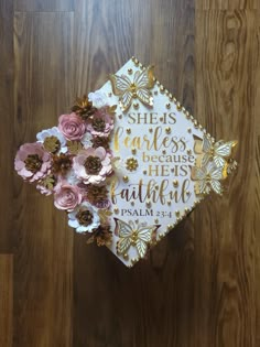 a graduation cap decorated with flowers on top of a wooden floor