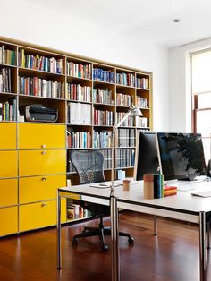 a desk with a computer on top of it in front of a bookshelf