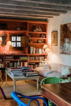 a living room filled with furniture and bookshelves next to a table in front of a window