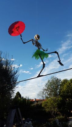 a skeleton kite is being flown in the air with a red umbrella over its head