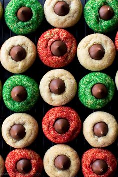 many different colored cookies with chocolates and sprinkles on top of them