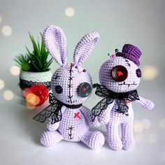 two crocheted stuffed animals sitting next to each other near a potted plant