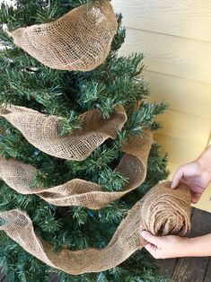 someone is decorating a christmas tree with burlocks and twine ribbons on it