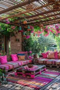 an outdoor living area with colorful cushions and rugs on the wooden floor, surrounded by greenery