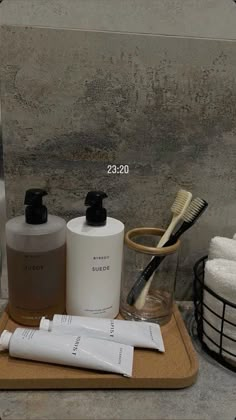 a wooden tray topped with personal care items on top of a bathroom counter next to a mirror