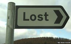 a close up of a street sign with trees in the back ground and clouds in the background